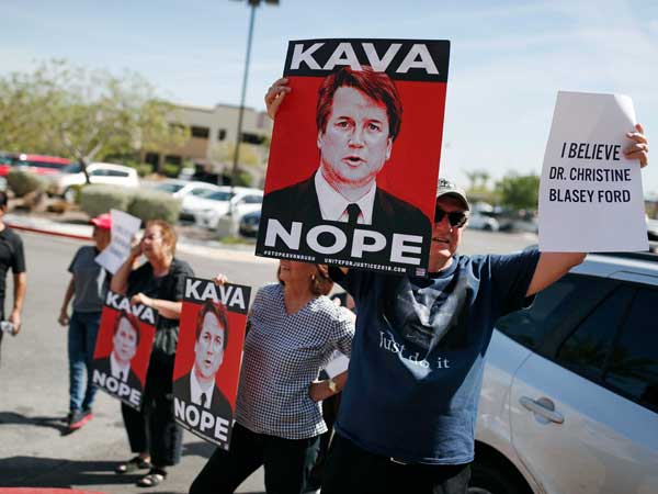 People hold signs during a protest against Kavanaugh outside the offices of Sen. Dean Heller, R-Nev. in Las Vegas.