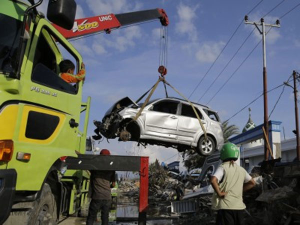 A damaged vehicle being carried on truck during clean-up operations after earthquake