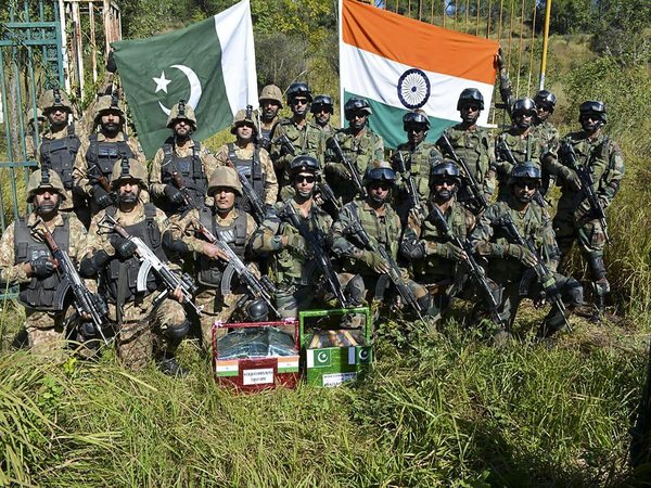 Indian and Pakistani army men pose for a group photograph after exchanging sweets in Poonch