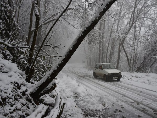 A vehicle moving on a snow-covered road during snowfall in Srinagar
