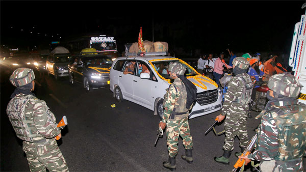Security personnel stand guard as a convoy carrying the first batch of Amarnath pilgrims leave for yatra from Jammu Security personnel stand guard as a convoy carrying the first batch of Amarnath pilgrims leave for yatra from Jammu