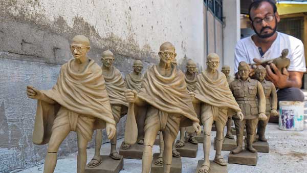 An artist gives finishing touch to clay sculptures of Mahatma Gandhi