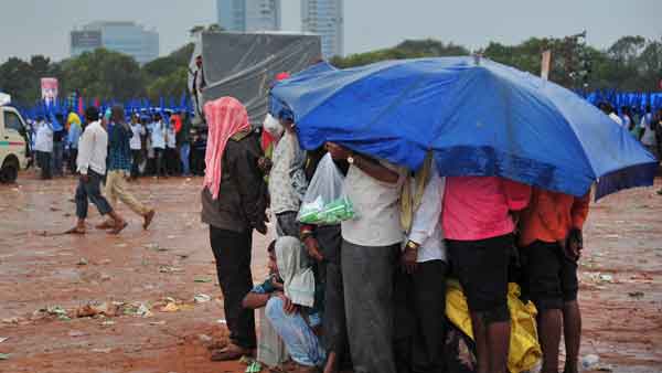 People take shelter under an umbrella as it rains in Bengaluru. People take shelter under an umbrella as it rains in Bengaluru.