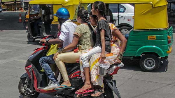 Two women and a child ride pillion on a bike without helmets Two women and a child ride pillion on a bike without helmets